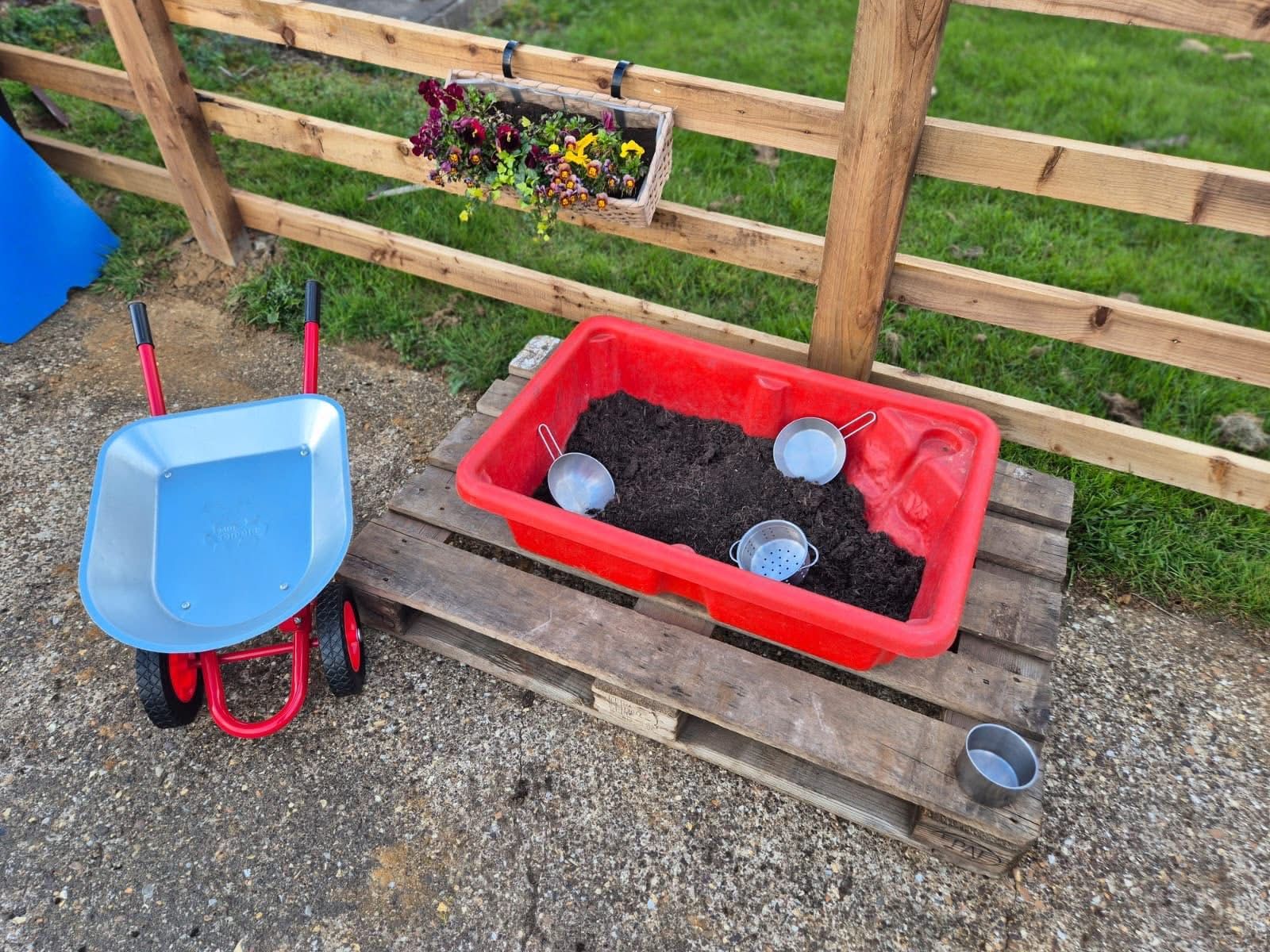 Children's planting trays and wheelbarrow in the garden